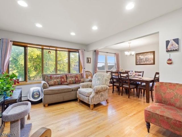 living room featuring light wood-type flooring, recessed lighting, a chandelier, and a baseboard heating unit