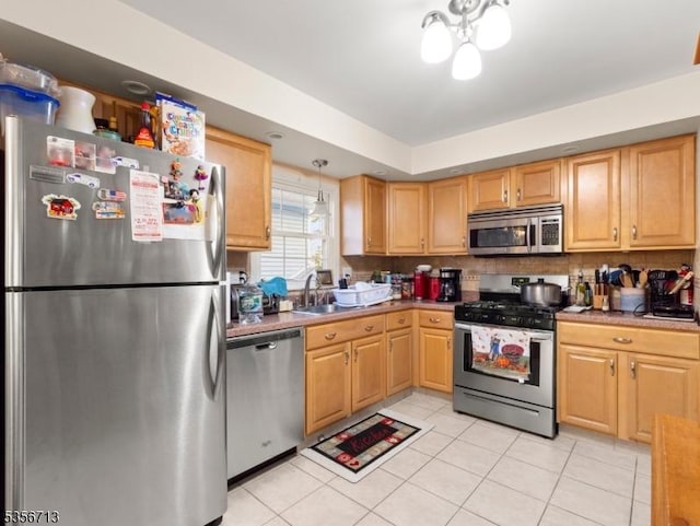 kitchen with stainless steel appliances, light tile patterned floors, decorative backsplash, and a sink