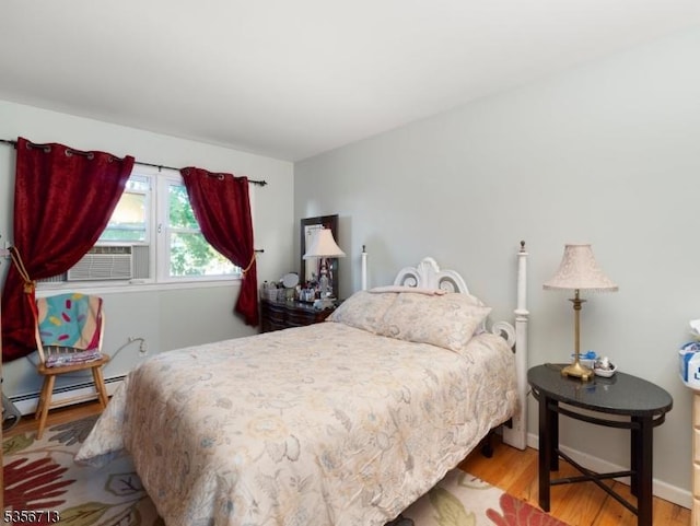 bedroom with a baseboard radiator, wood finished floors, and cooling unit