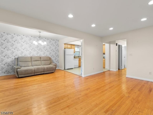 living room featuring wallpapered walls, light wood-style flooring, a chandelier, baseboards, and recessed lighting