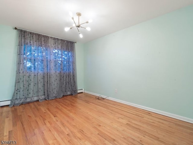 unfurnished room featuring a chandelier, wood finished floors, a baseboard radiator, and baseboards