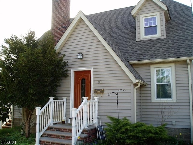 view of front of home with roof with shingles and a chimney