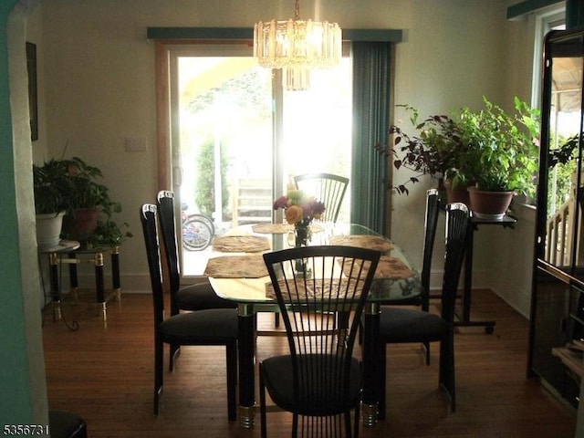 dining area with healthy amount of natural light, a chandelier, and wood finished floors