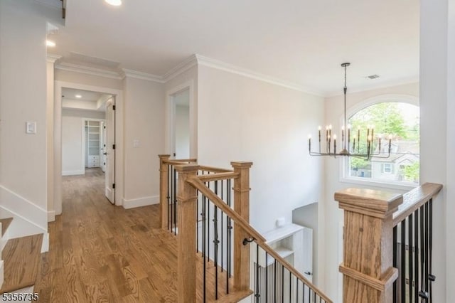 hall featuring an upstairs landing, a chandelier, wood finished floors, crown molding, and baseboards