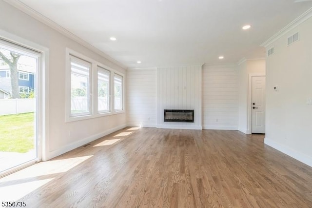 unfurnished living room featuring crown molding, baseboards, light wood-style flooring, a fireplace, and recessed lighting