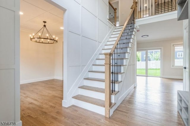stairway featuring ornamental molding, a chandelier, wood finished floors, and baseboards