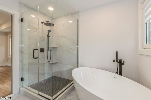 full bath with a freestanding tub and a marble finish shower