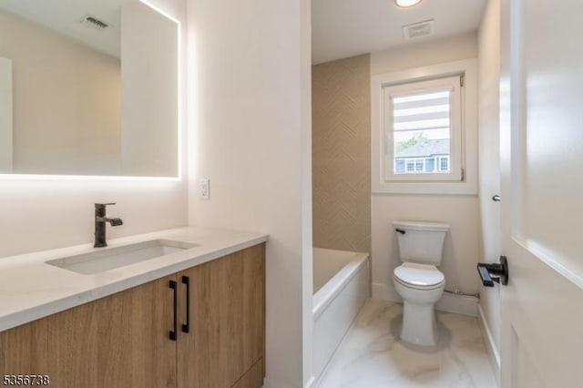 bathroom with toilet, vanity, marble look tiles, a tub, and baseboards