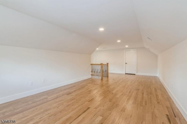 additional living space with vaulted ceiling, light wood-type flooring, baseboards, and recessed lighting