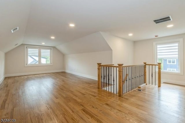 additional living space featuring wood finished floors, vaulted ceiling, baseboards, and recessed lighting