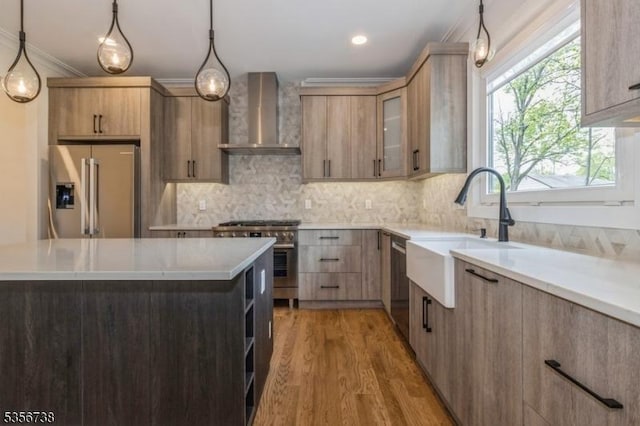 kitchen featuring premium appliances, wall chimney exhaust hood, a sink, light countertops, and crown molding