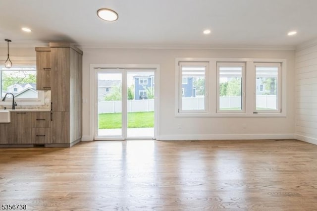 unfurnished living room with ornamental molding, light wood-style flooring, baseboards, and recessed lighting