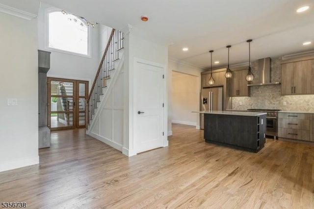 kitchen with wall chimney exhaust hood, a center island, light countertops, ornamental molding, and baseboards