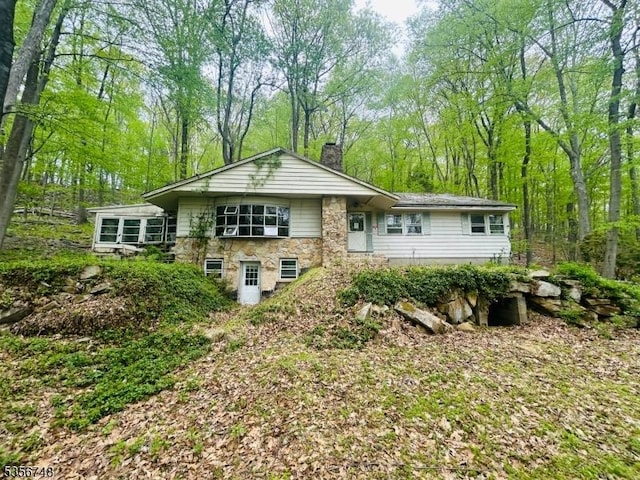 rear view of house with a chimney and stone siding