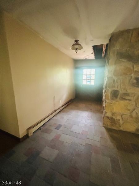 unfurnished room with a baseboard heating unit