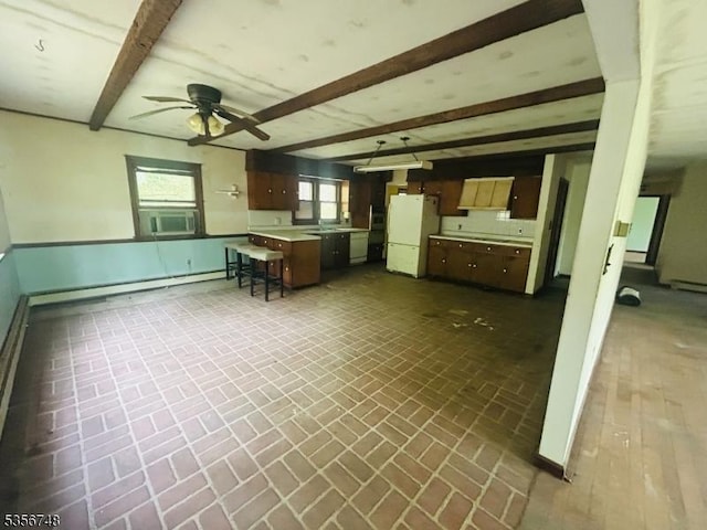 kitchen with freestanding refrigerator, baseboard heating, brick patterned floors, beam ceiling, and ceiling fan