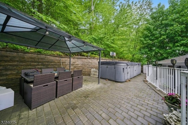 view of patio / terrace with a hot tub, a gazebo, and outdoor dining area