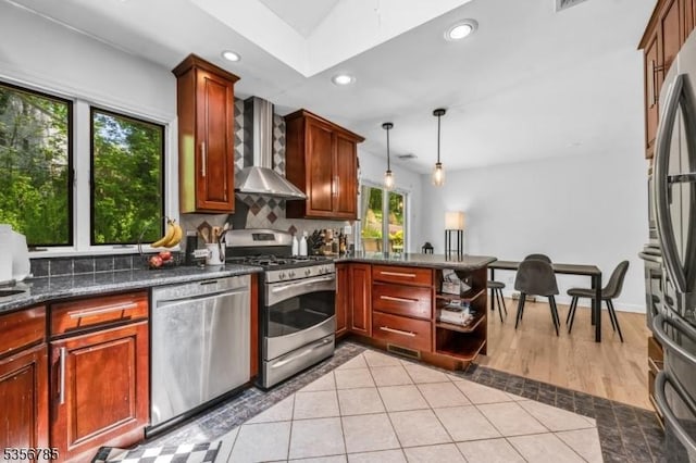 kitchen with appliances with stainless steel finishes, wall chimney exhaust hood, decorative backsplash, recessed lighting, and a peninsula