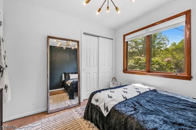 bedroom featuring a chandelier, light wood-style floors, baseboards, and a closet