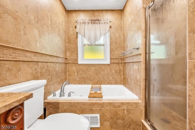 bathroom with tile walls, a shower stall, toilet, a garden tub, and vanity