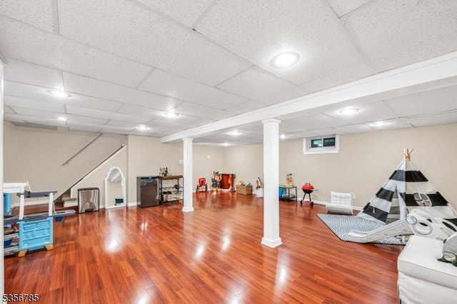 exercise area featuring wood finished floors, baseboards, and a paneled ceiling