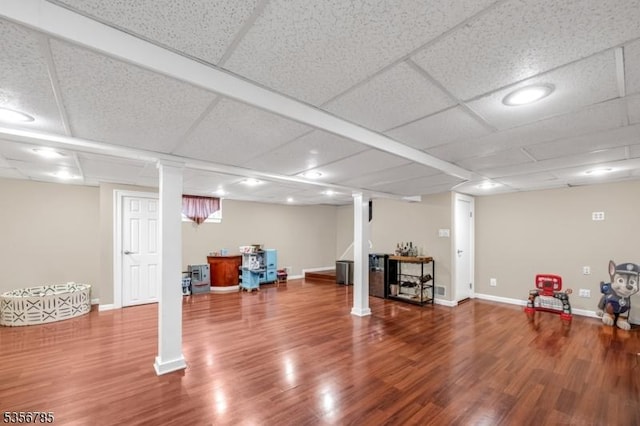 finished below grade area with wood finished floors, baseboards, and a drop ceiling