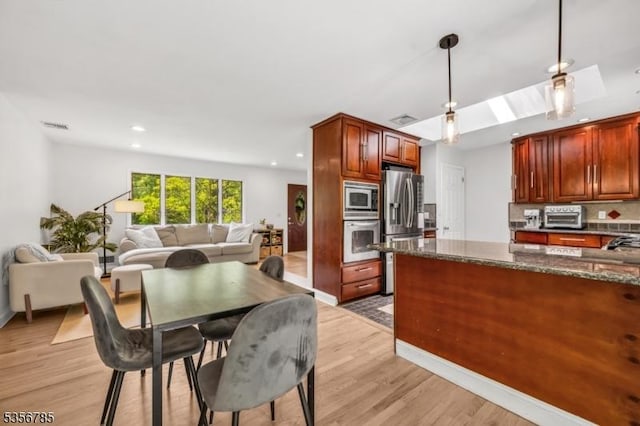 kitchen with appliances with stainless steel finishes, light wood-style flooring, open floor plan, decorative light fixtures, and recessed lighting