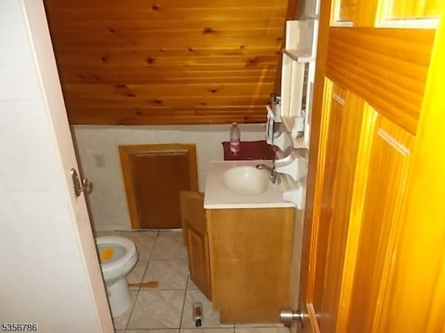 half bathroom featuring toilet, vanity, tile patterned floors, and wooden ceiling