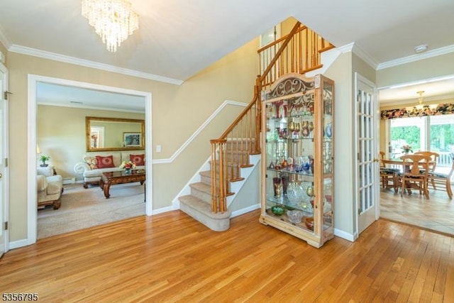stairs featuring a chandelier, wood finished floors, crown molding, and baseboards