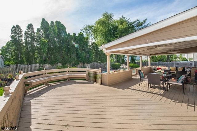wooden terrace with a fenced backyard and outdoor dining space