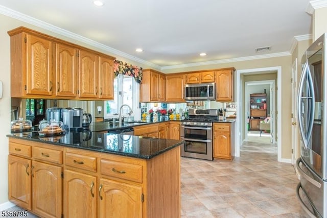 kitchen with appliances with stainless steel finishes, a peninsula, dark stone countertops, crown molding, and a sink