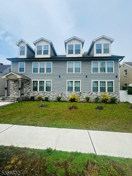 view of front of home with a front yard and stone siding