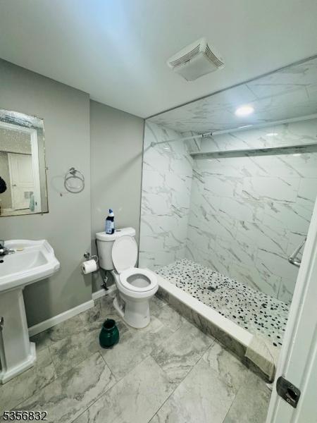 full bath with marble finish floors, a marble finish shower, toilet, and baseboards