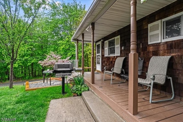 wooden terrace featuring a lawn and covered porch