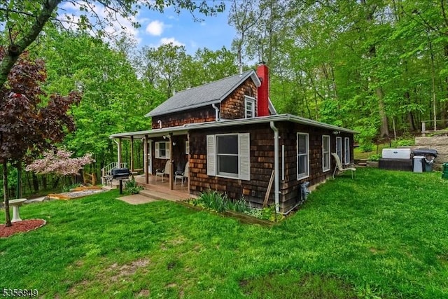 back of property with a yard, a chimney, and covered porch