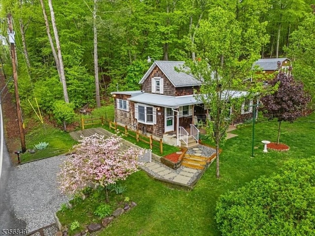 view of front of property with a porch, a front lawn, and a wooded view