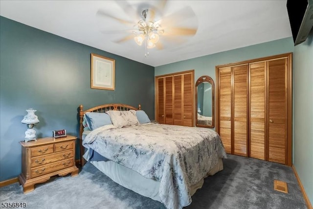 bedroom with two closets, carpet flooring, ceiling fan, and baseboards
