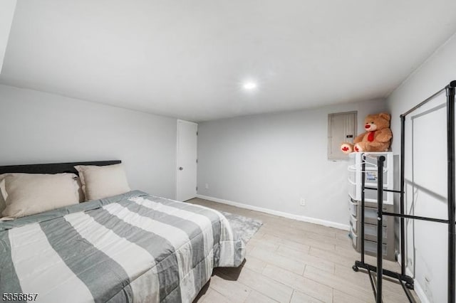 bedroom with electric panel, baseboards, and light wood finished floors