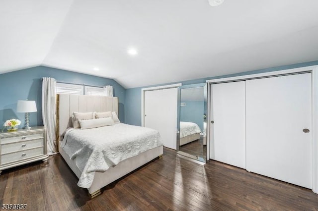 bedroom with lofted ceiling, two closets, and wood finished floors