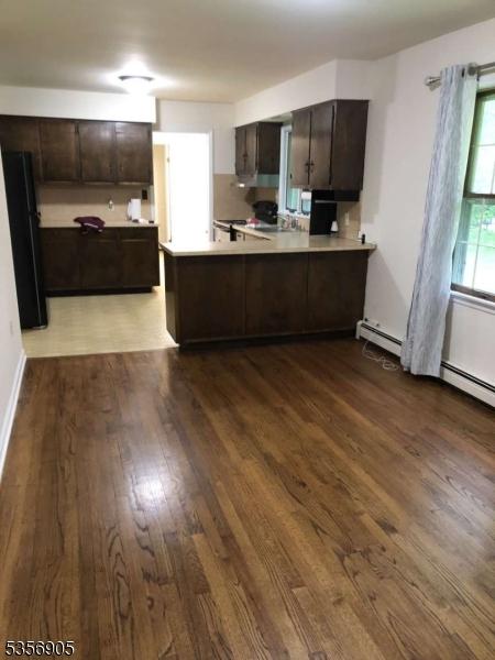89 Ridge Rd, Jefferson Twp, NJ 07438 - kitchen with dark brown cabinets, a peninsula, dark wood-style flooring, and light countertops