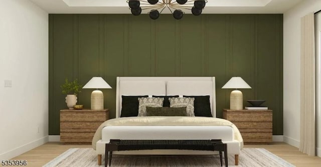 bedroom with a decorative wall, light wood-type flooring, a chandelier, and baseboards