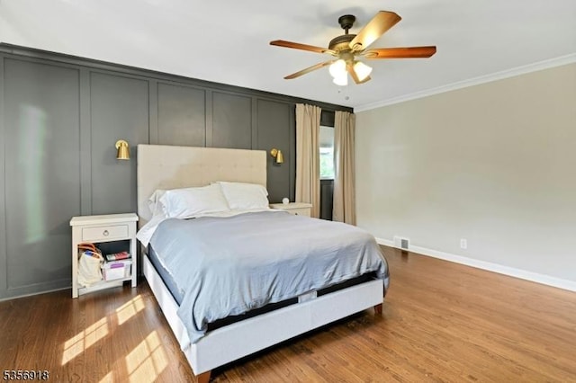 bedroom with ornamental molding, baseboards, wood finished floors, and a ceiling fan
