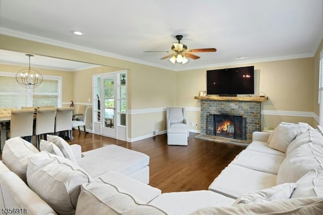 living area with wood finished floors, a fireplace, ceiling fan, a chandelier, and ornamental molding
