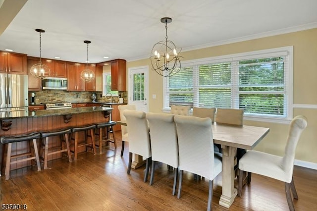 dining area with healthy amount of natural light, a chandelier, crown molding, and dark wood-style floors
