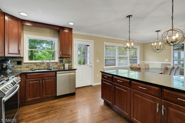 kitchen featuring appliances with stainless steel finishes, a sink, tasteful backsplash, a chandelier, and crown molding