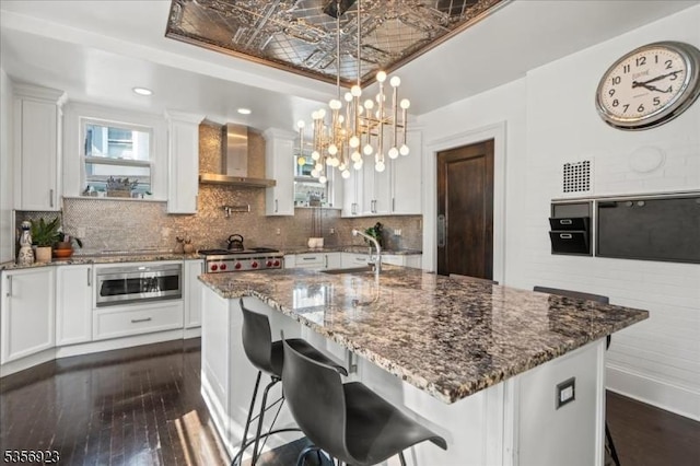 12 Harrison Ave, Montclair Twp, NJ 07042 - kitchen with wall chimney exhaust hood, a sink, appliances with stainless steel finishes, white cabinetry, and dark wood-style flooring