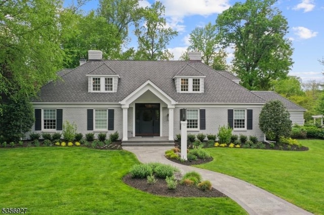 cape cod-style house featuring a front yard, a chimney, and brick siding