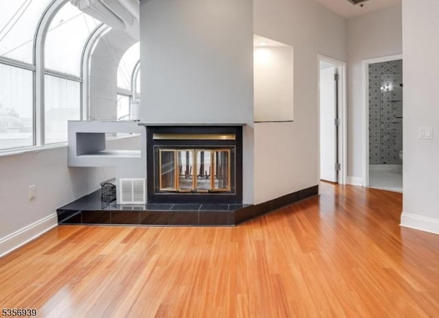 detailed view of wood finished floors, a tiled fireplace, and baseboards