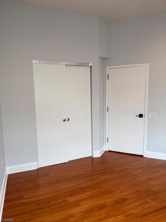 unfurnished bedroom with wood finished floors, a closet, and baseboards