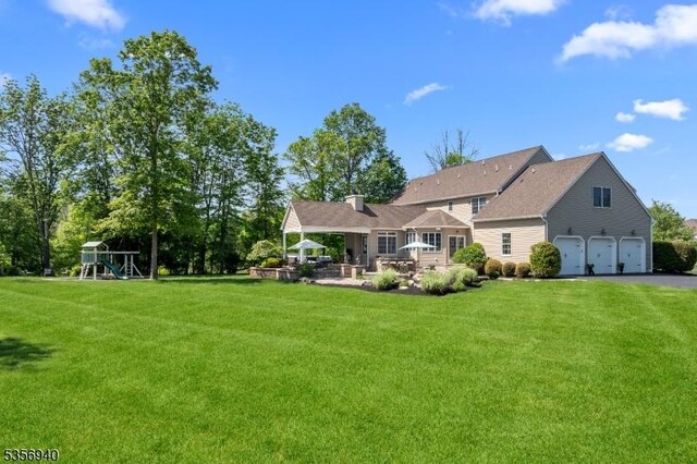 28 Handler Ct, Montgomery Twp, NJ 08502 - back of property with a lawn, a playground, an attached garage, and a chimney